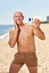 bald man on the beach with sunblock. Dangerous ultraviolet concept
