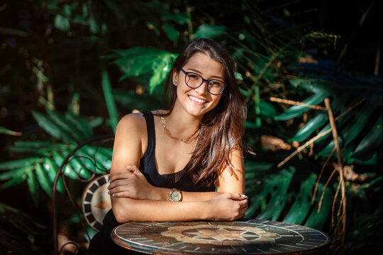 beautiful young Latina woman sitting at a table with jungle type background