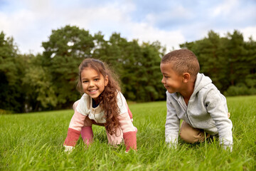 Fototapeta premium childhood, leisure and people concept - happy smiling little boy and girl having fun at park