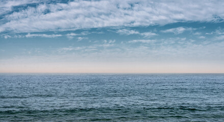 Fototapeta premium The surface of the sea under a cloudy blue sky. Blue wave surface of the sea going to the horizon.