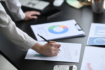 Cropped shot professional businesswoman checking and analyzing financial graph at her workplace