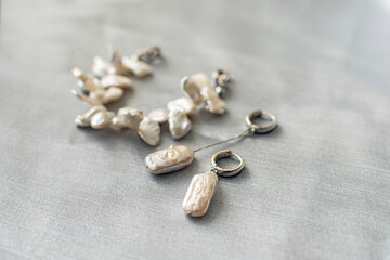 Luxury baroque pearl earrings and bracelet on a silver background.