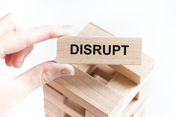 DISRUPT text on a wooden bar in the hands of a person, a business concept