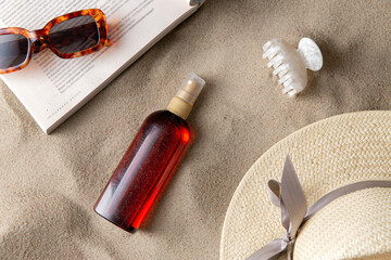leisure and summer holidays concept - open magazine, sunscreen, hair clip and sunglasses on beach...