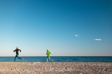 Obraz premium A child with his mother runs along the beach