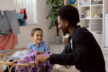 Son helps dad with household chores, man sort laundry, fold clothes, prepare for drying, spend time together in the bathroom teaching the girl how to use the washing machine.