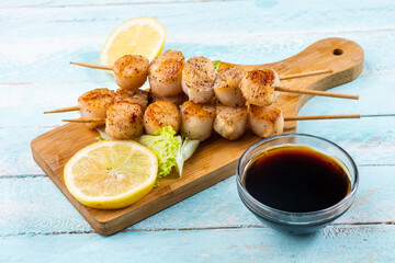 Grilled scallops served with soy sauce and lemon. Scallops on skewers.