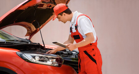 Car mechanic is using a tablet computer to check the car errors and problems and fix it. .