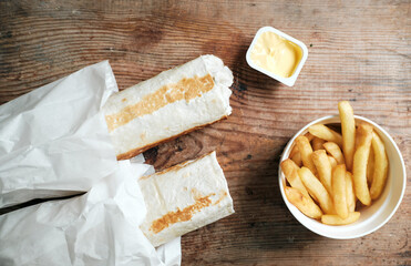 two doners and french fries with cheese sauce on a wooden background, top view. Shawarma on a wooden table. Food delivery