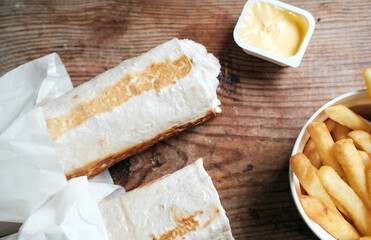 two doners and french fries with cheese sauce on a wooden background, top view. Shawarma on a wooden table. Food delivery
