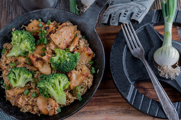 Fitness meal with chicken breast, brown rice and broccoli in a rustic iron pan
