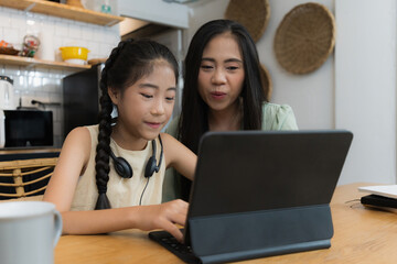 Family and home school concept. Asian mother teach her daughter using application on digital tablet at home.