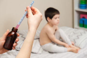 The pediatrician or mother types in a measuring syringe the medicine for cough or temperature syrup for the child