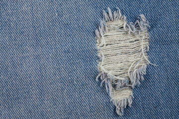 Blue jeans background closeup view to torn texture.