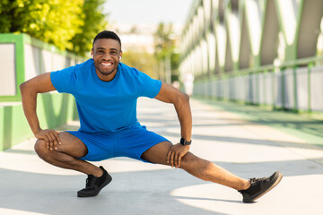 A black runner with a beautiful figure is warming up before a cardio workout with lunges to stretch...
