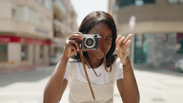 Young african american woman using vintage camera at street