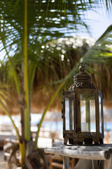 Vintage lantern with candle on a wooden table at beach club.