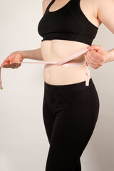 A woman measures the circumference of the abdomen with a centimeter tape, close-up. Slimming concept