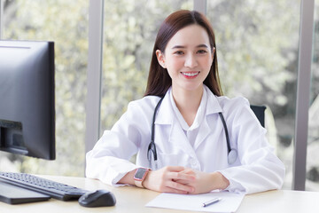 Asian professional woman doctor sitting smile wearing a white robe and stethoscope while waiting for a patient at the hospital health care concept.