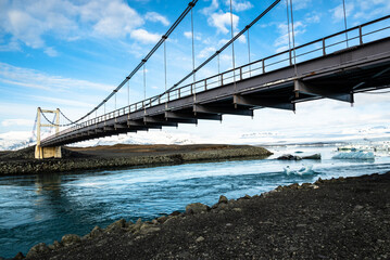 Icebergs floating under the suspension bridge of Route 1 / Hringvegur (Ring Road) over the river that connects the Jökulsárlón glacier lagoon with the Ocean, Vatnajökull National Park, Iceland