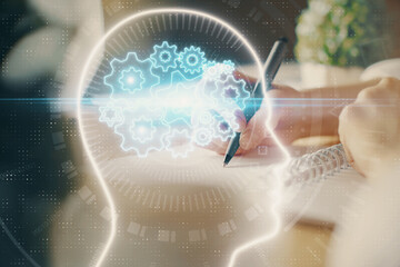 Multi exposure of writing hand on background with brain hologram. Concept of self learning.