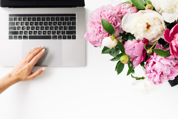 woman using laptop with blank screen and peony flowers on white background