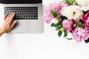 woman using laptop with blank screen and peony flowers on white background