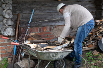 A man puts firewood from a cart into a firewood storage