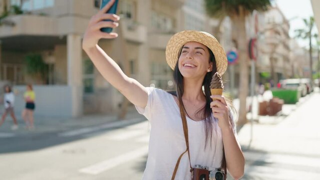 Young hispanic woman tourist making selfie by the smartphone eating ice cream at street