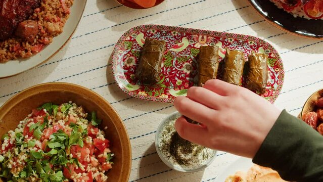 Eating dolma with sour cream close-up, meat in grapes leaves, middle eastern national traditional food. Muslim family dinner, Ramadan, iftar. Arabian cuisine.