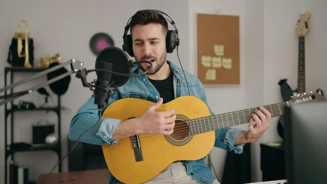 Young hispanic man singing song playing classical guitar at music studio