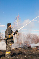 a brave firefighter puts out a grass fire in the villages close to the metropolis with the help of a water hydrant