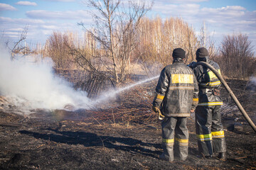 a brave firefighter puts out a grass fire in the villages close to the metropolis with the help of...