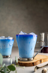 Ice latte with blue butterfly pea. Refreshing blue matcha latte in a glass cups with ice cubes.