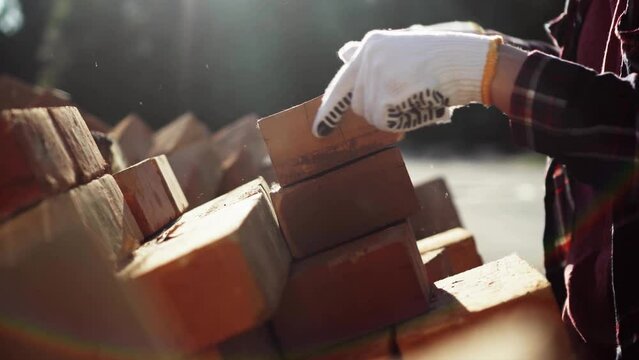 Builder's hands are stacking red bricks in a large warehouse. Pile of building material bricks in orange bright color, Construction industry concept building construction renovation
