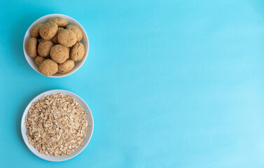 Flatlay oatmeal, oatmeal cookies on a white plate on a blue background, top view, healthy eating concept, and making cereal or cookies. A place for text on the right. High-quality photo