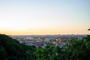 Urban skyline under sunset sky view from green tree hills