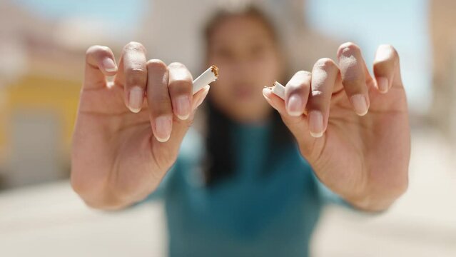 Young african american woman breaking cigarette at street