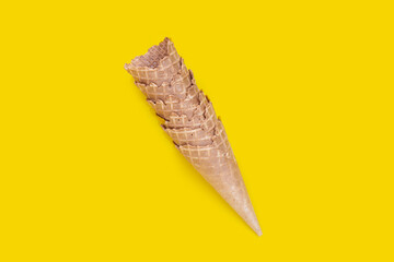 Empty ice cream cone on yellow background.