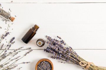 Fototapeta na wymiar open medical bottle with a dropper with organic natural lavender oil and on a white wooden background with a bouquet of dry lavender.