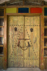 Old light green wooden door with colored glasses, chain and padlocks