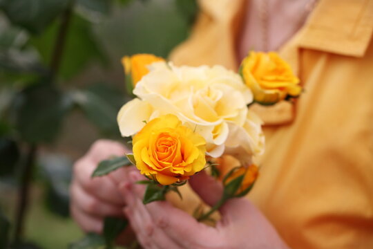 Woman's hands with a bouquet of yellow roses