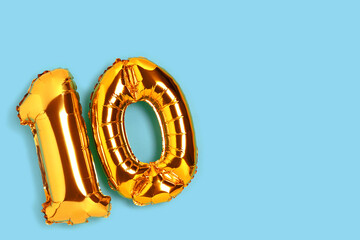 Number 10 golden balloon with copy space. Ten years anniversary celebration concept on a blue...