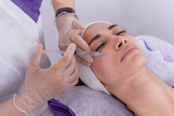 Obraz na płótnie Canvas portrait of a young woman receiving facial mesotherapy treatment to smooth wrinkles. an anti-aging injection to firm up the skin