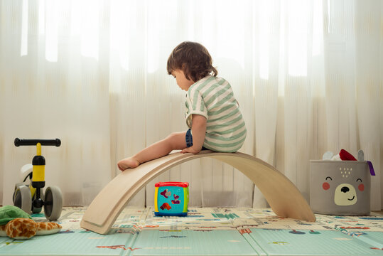 Rear view of a female toddler playing with a balance board at a montessori playroom.
