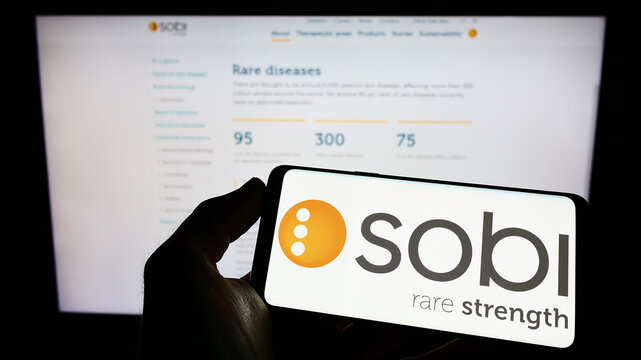 Stuttgart, Germany - 06-06-2022: Person holding cellphone with logo of company Swedish Orphan Biovitrum AB (Sobi) on screen in front of business webpage. Focus on phone display.