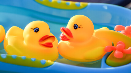 Red beak of a yellow plastic duck in a blue bath