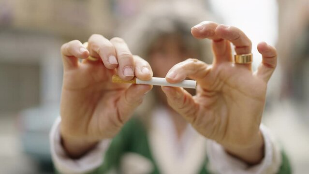 Middle age woman breaking cigarette at street