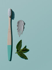 Bamboo Toothbrush, mint toothpaste and peppermint on blue background, organic eco wooden toothbrush with copy space