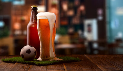 Buttle and glass of beer, soccer ball on green grass